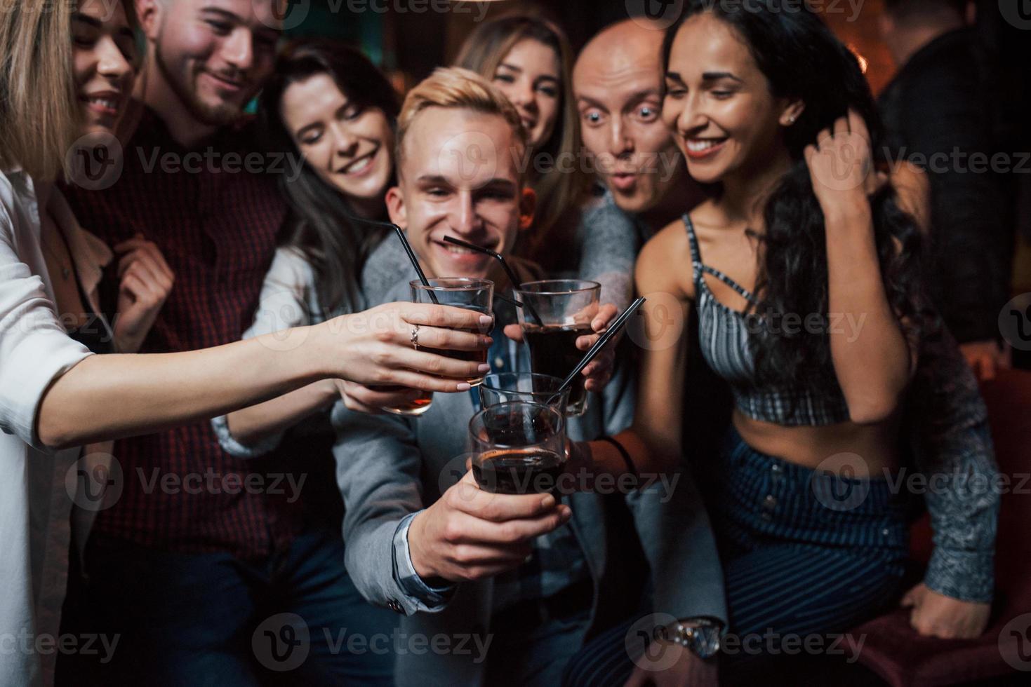 Luxus-Whisky. Gruppe junger Freunde, die im Nachtclub lächeln und anstoßen foto