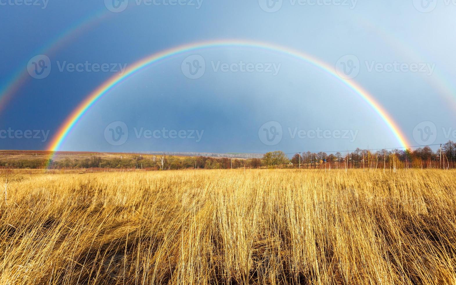 schöner voller Regenbogen über Bauernhoffeld im Frühjahr foto