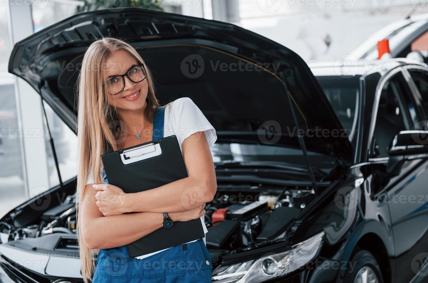 Eyewear sitzt fantastisch auf diesem Mädchen. manager mit notizblock, im weißen hemd und in blauer uniform steht mit aufgesetzter verdeck vor auto foto