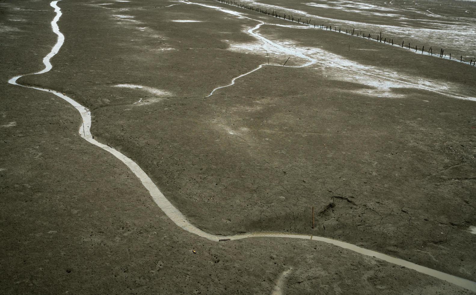 Landschaft aus Küstenschlamm. Einsamkeit. Strand bei Flut. Wasserkanal mit natürlichem Muster. grauer Lehm. Küstenökosysteme. Delta-Mündung. foto