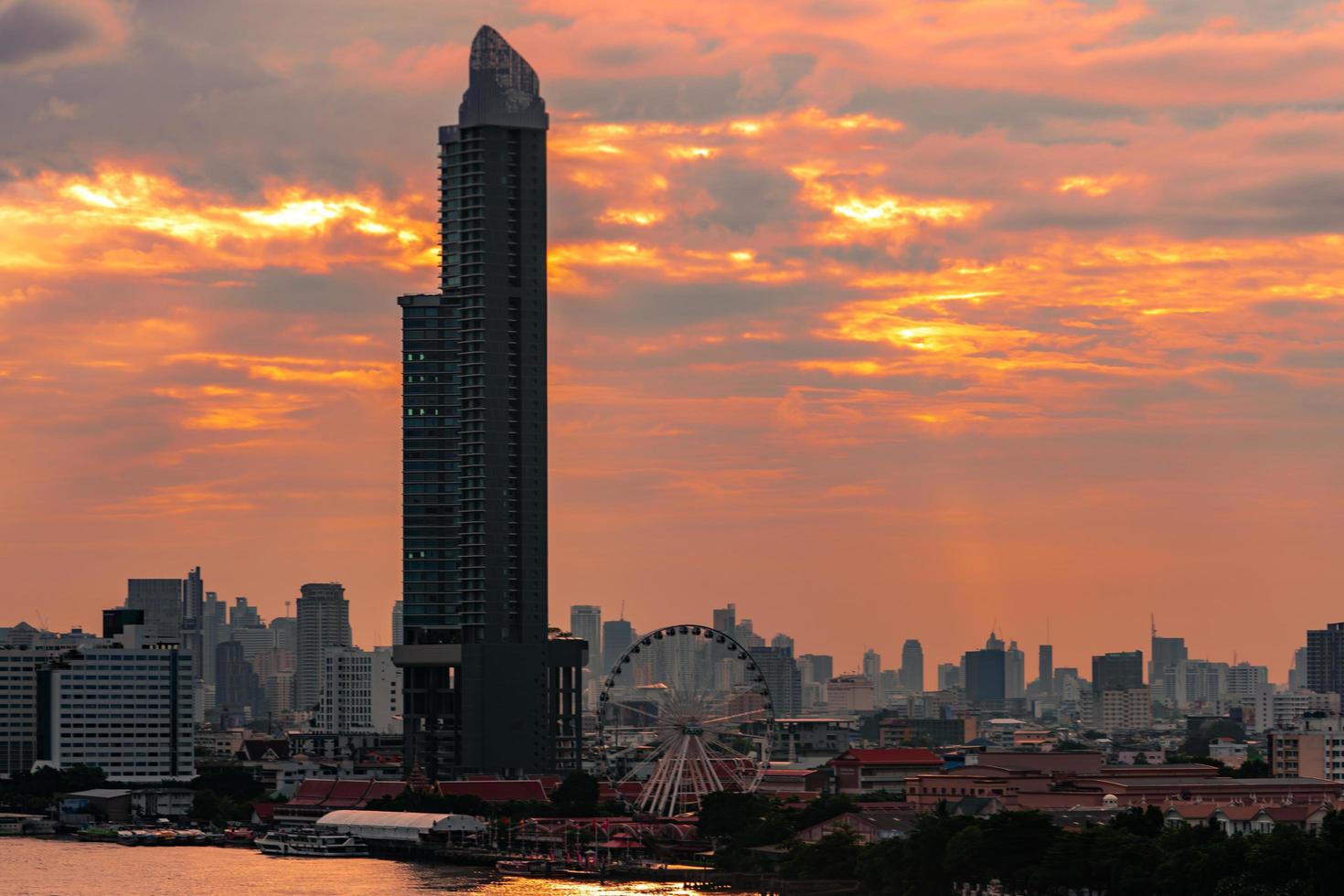 stadtbild eines modernen gebäudes in der nähe des flusses morgens mit orangefarbenem sonnenaufgangshimmel und wolken in bangkok in thailand. moderne architektur bürogebäude stadtbild. foto