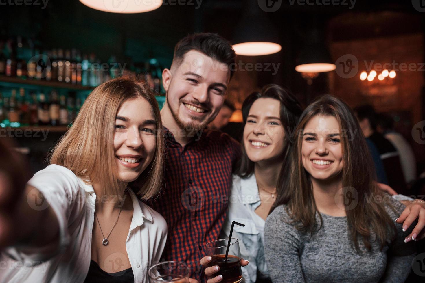 Foto wie vom Telefon. freunde, die selfie im schönen nachtclub machen. mit Getränken in den Händen