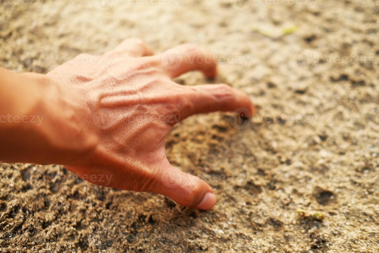 männliche Hand, die etwas im Sand berührt foto