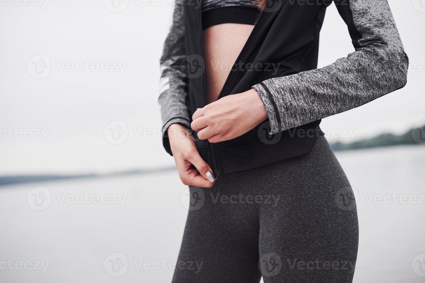 Zugeschnittenes Foto eines Fitness-Mädchens, das nach dem morgendlichen Lauf in der Nähe des Sees posiert