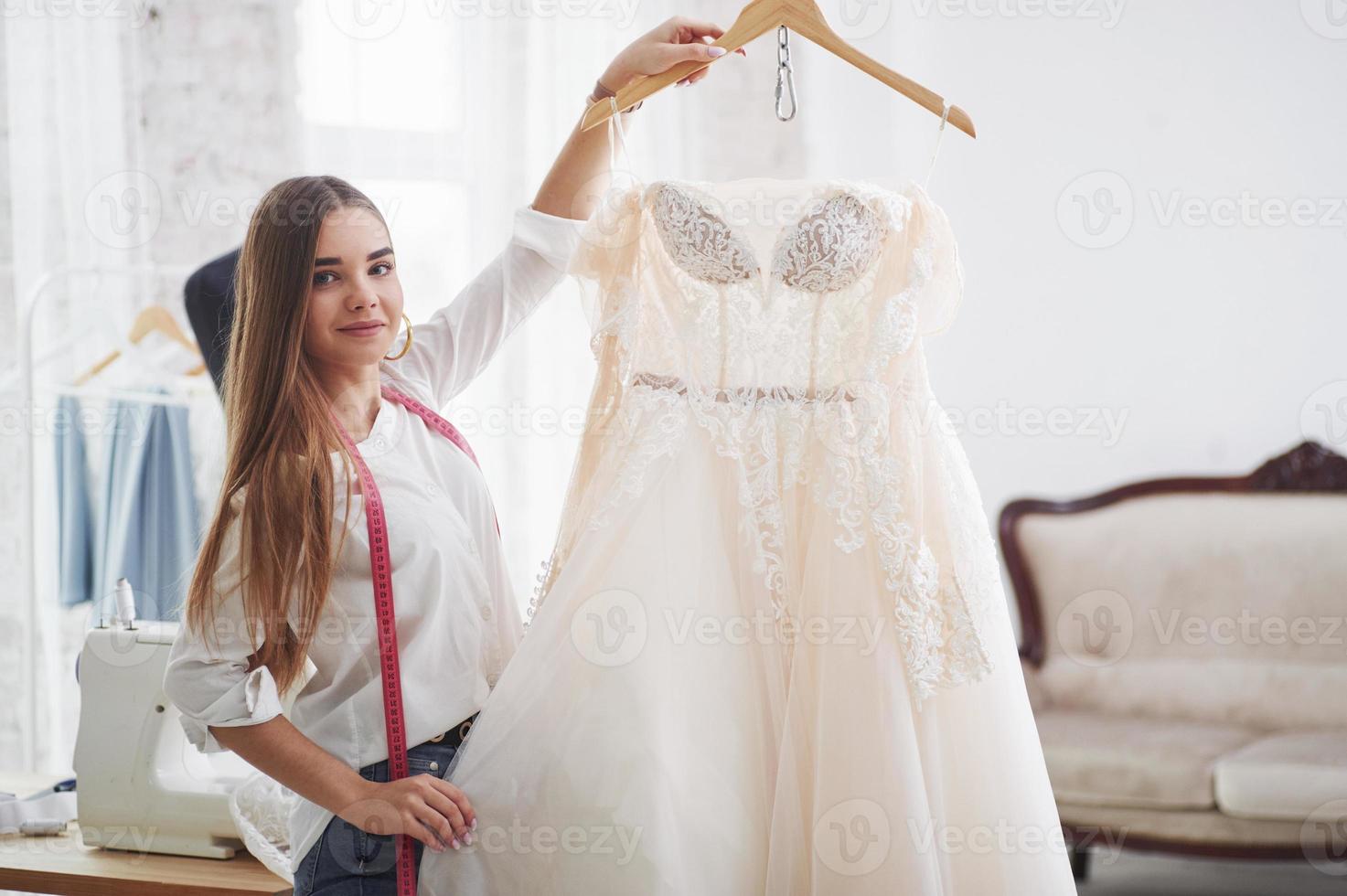 stolz auf die fertige Arbeit. Modedesignerin zeigt Ergebnis ihrer Arbeit in der Werkstatt foto