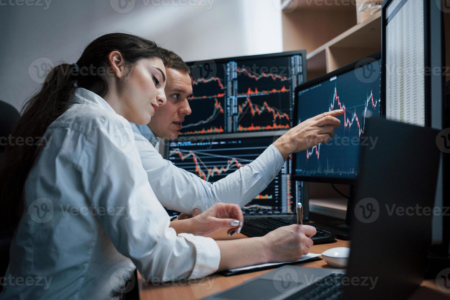 Ein Team von Börsenmaklern führt ein Gespräch in einem Büro mit mehreren Bildschirmen foto