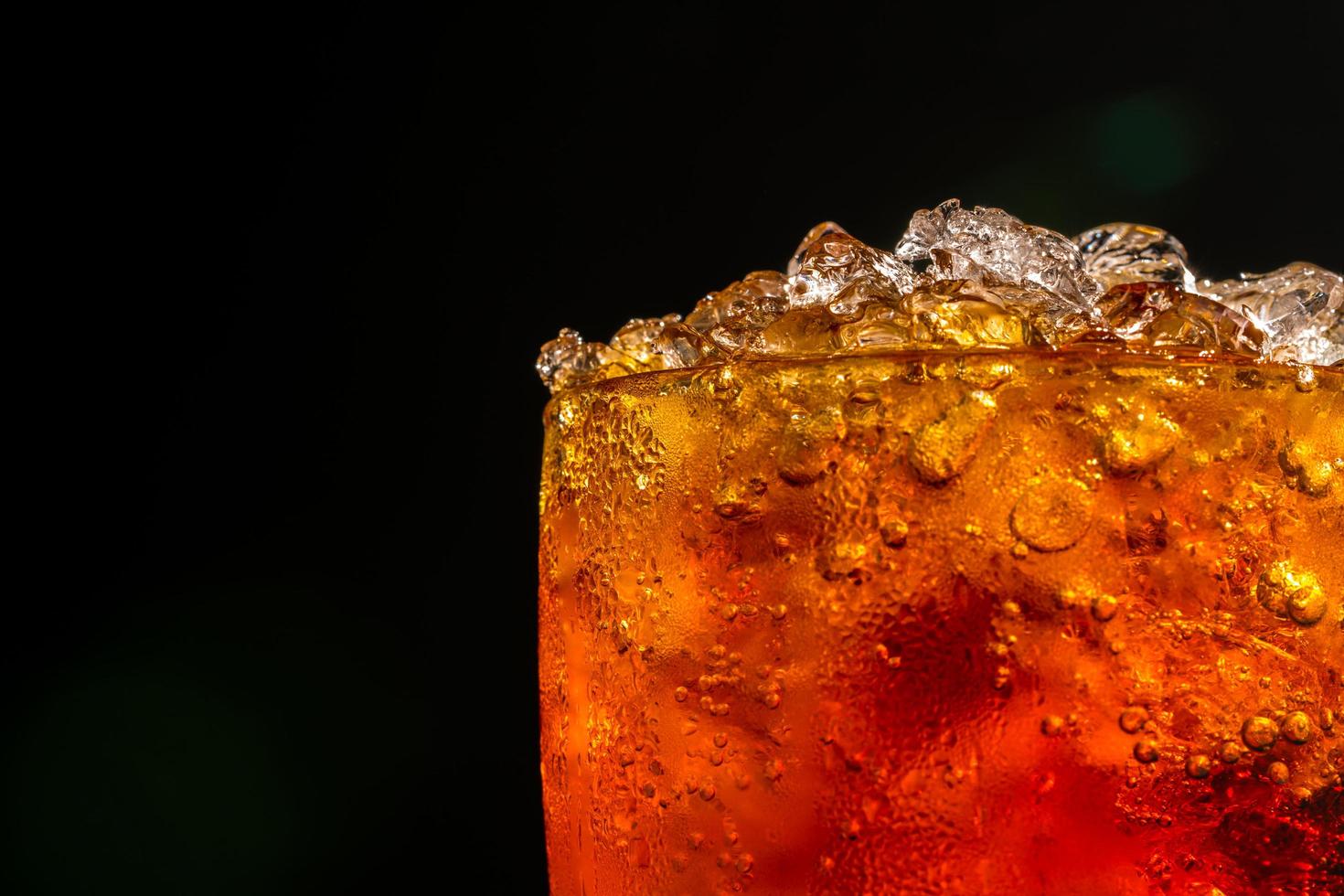 Erfrischungsgetränk mit zerstoßenen Eiswürfeln im Glas isoliert auf dunklem Hintergrund mit Kopierraum. Auf der transparenten Glasoberfläche befindet sich ein Wassertropfen. foto