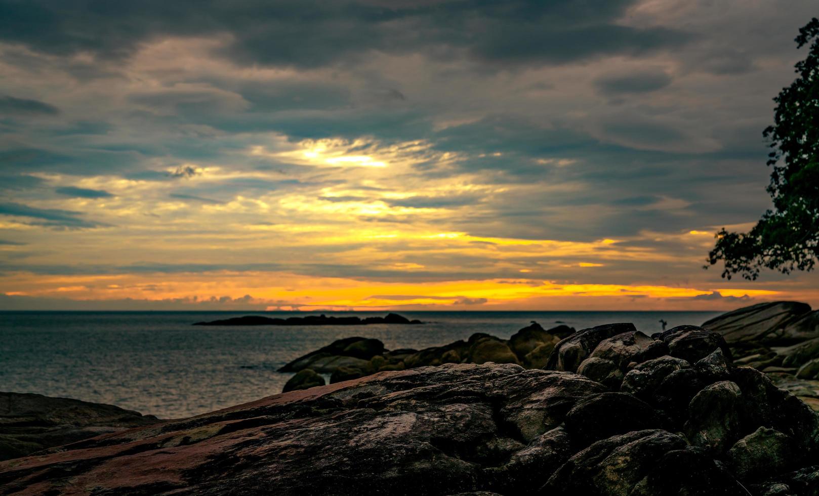 schöner steinstrand morgens mit goldenem sonnenaufganghimmel. friedliche und ruhige Szene. Landschaft mit ruhigem Meer am Morgen. Meereslandschaft mit Skyline. tropisches meer. Schönheit in der Natur. Felsenstrand. foto