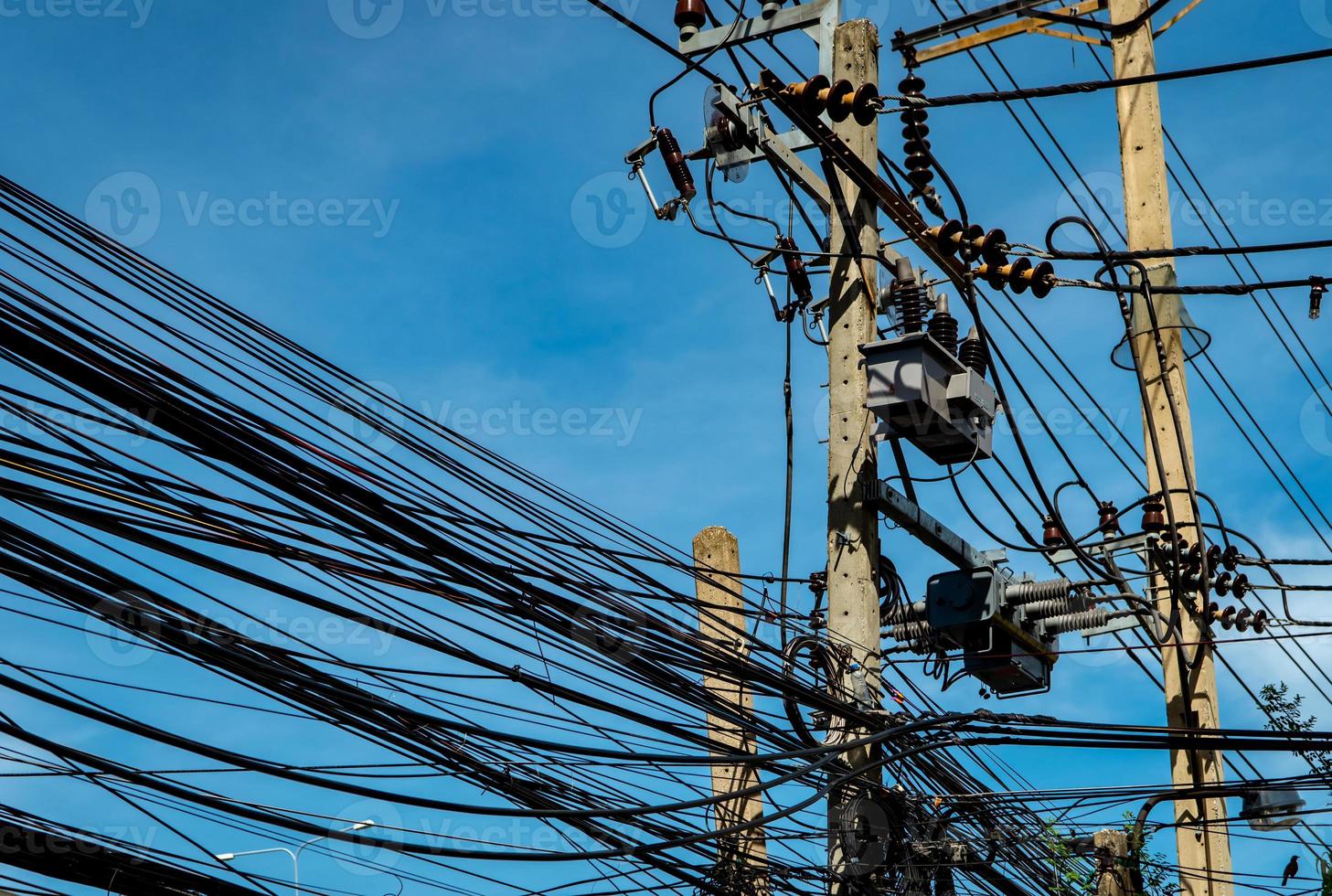 dreiphasiger elektrischer Strom zur Übertragung von Strom durch Stromnetze. elektrische Energie für die unterstützende Fertigungsindustrie. elektrische hochspannungsmasten mit drahtleitungen und kabelleitungen gegen blauen himmel foto