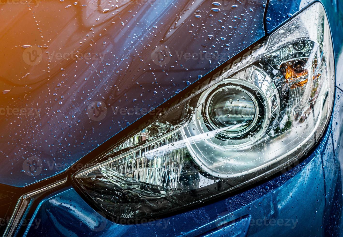 blaues kompaktes suv-auto mit sport und modernem design werden mit wasser gewaschen. Geschäftskonzept für den Autopflegedienst. Auto nach der Reinigung mit Hochdruckwasserspray mit Wassertropfen bedeckt foto