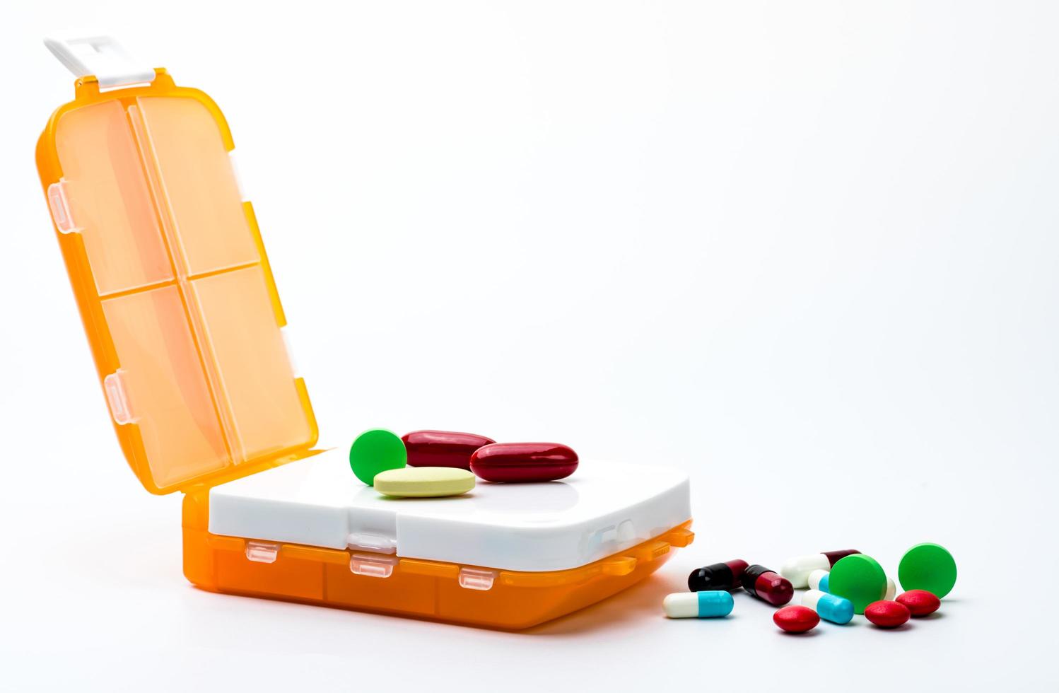 orange Pillenbox mit bunten Kapselpillen isoliert auf weißem Hintergrund mit Kopierraum. bereiten sie medizin vor der arbeit vor oder reisen sie ins ausland. foto
