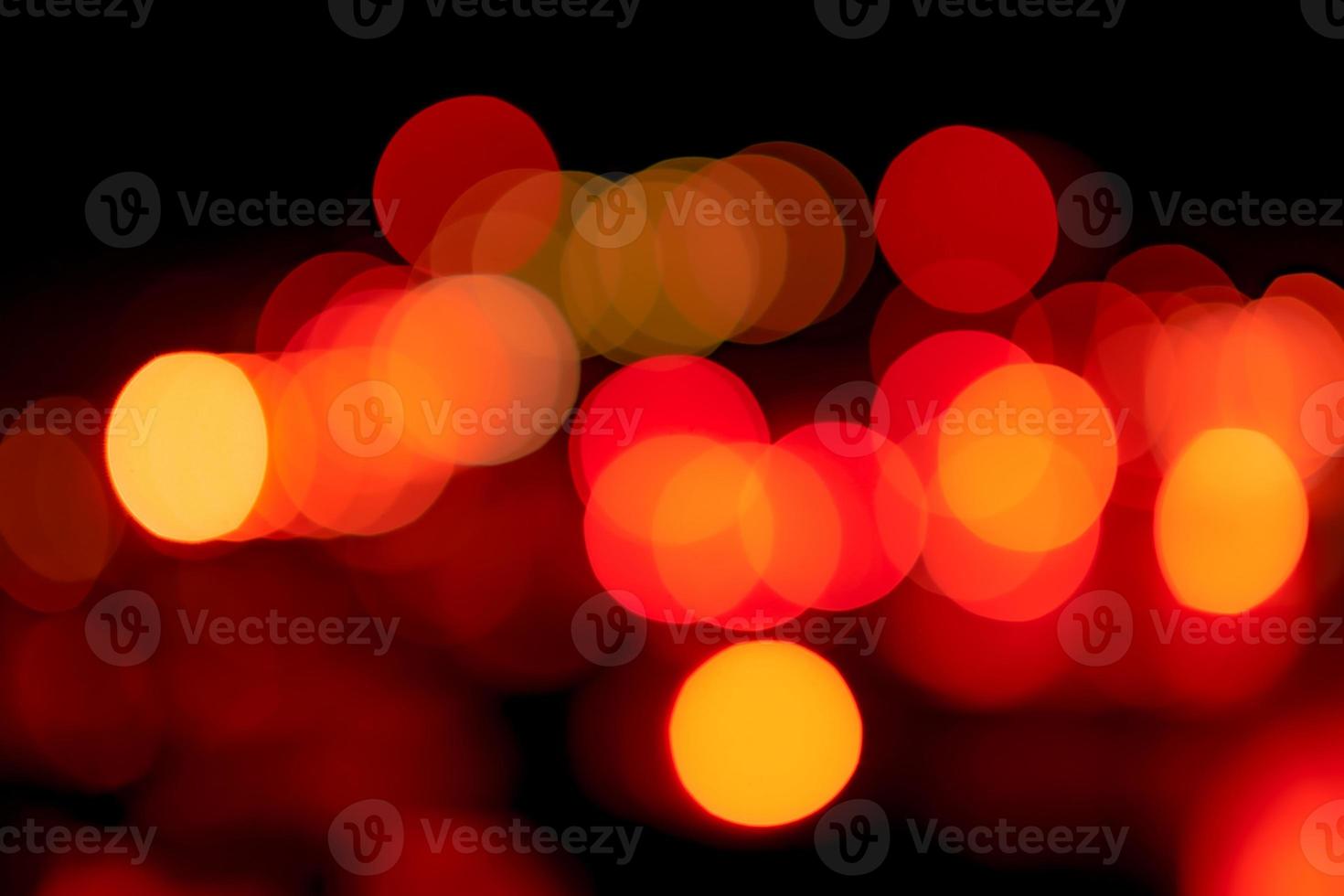 Unscharfes rotes und orangefarbenes Bokeh auf dunklem Hintergrund. abstrakter hintergrund des stadtlichts. Bokeh-Licht mit Kreis-Bokeh-Muster. rotes und gelbes licht auf schwarz. Defokussiertes Bokeh-Licht in der Stadt bei Nacht. foto