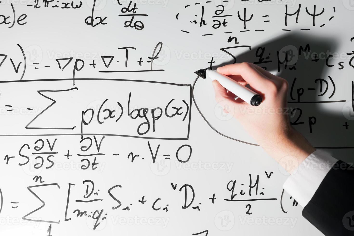 Mann schreibt komplexe mathematische Formeln auf Whiteboard. Mathematik und Naturwissenschaften foto