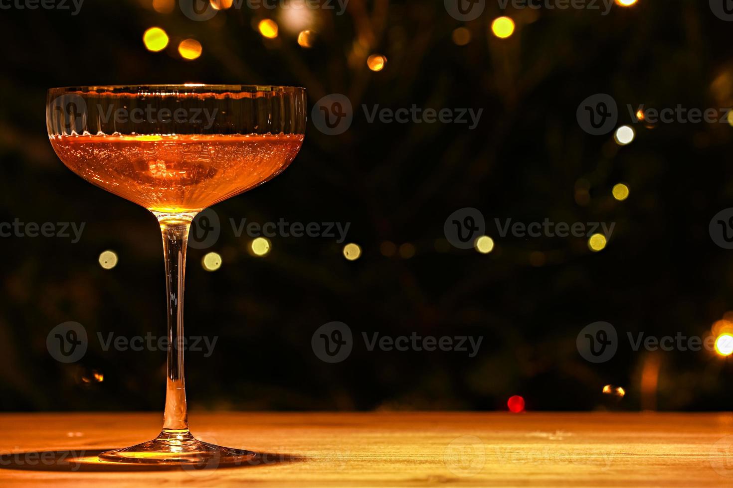 schönes glas champagner gegen bokeh beleuchtet hintergrund mit einem geschmückten weihnachtsbaum. frohes neues jahr 2022. weihnachts- und neujahrsferien hintergrund, wintersaison foto
