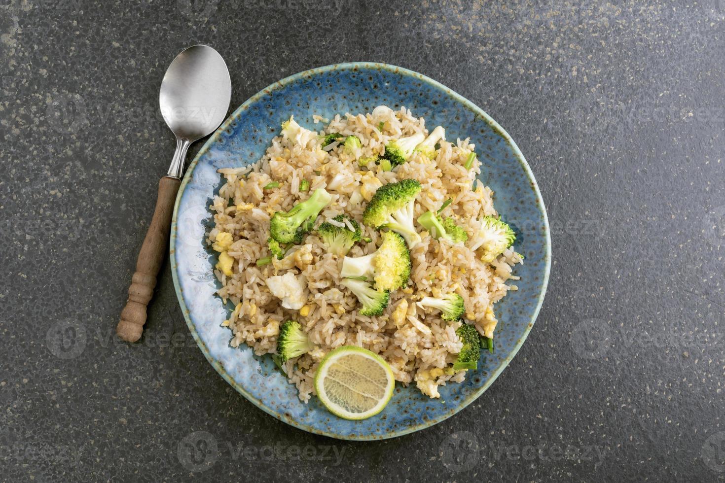 vegetarisches gesundes Essen gebratener Reis mit Brokkoli-Ei in der Platte auf schwarzem Steinhintergrund. foto