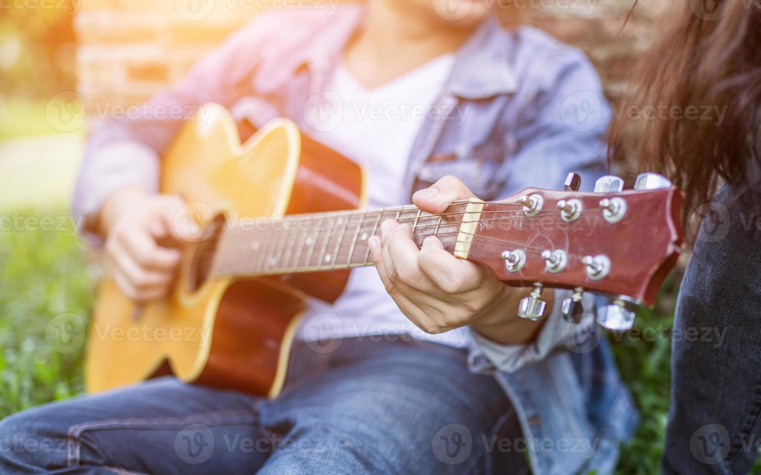 junger Hipster-Mann, der Gitarre spielt, um sich in seinem Urlaub zu entspannen, mit natürlicher und frischer Luft zu genießen. foto