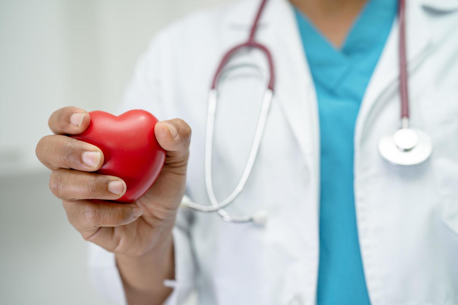 Arzt, der ein rotes Herz in der Krankenstation hält, gesundes, starkes medizinisches Konzept. foto