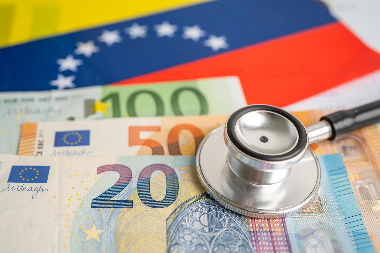 Schwarzes Stethoskop mit Euro-Banknoten auf venezolanischem Flaggenhintergrund, Geschäfts- und Finanzkonzept. foto