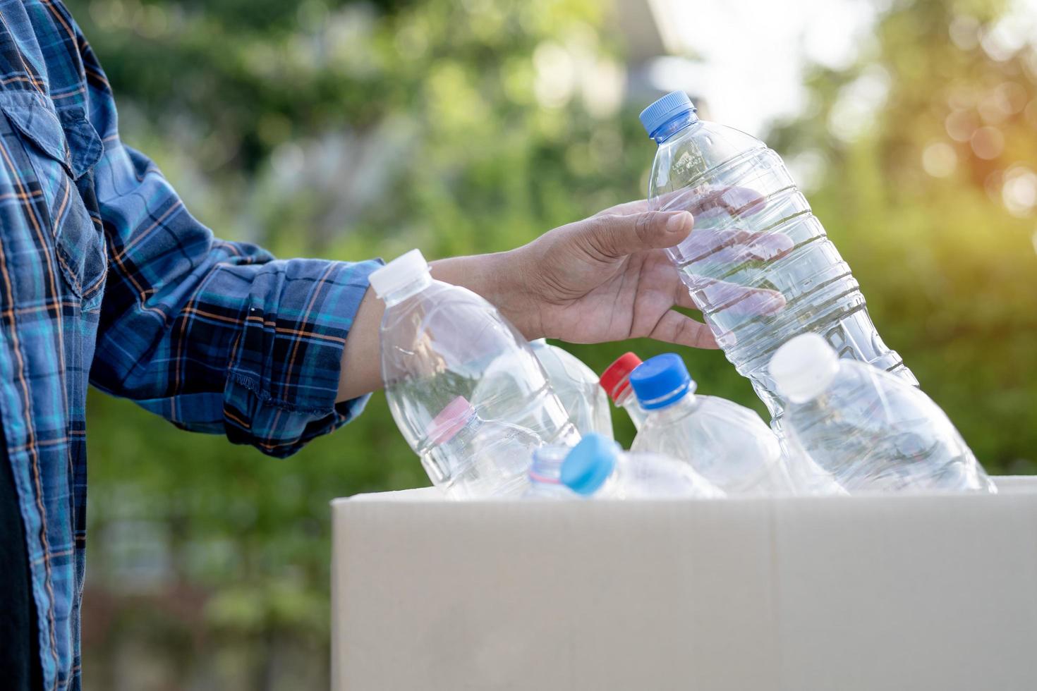 freiwillige asiatische frau trägt wasserplastikflaschen in den müll der mülltonne im park, recycelt das ökologiekonzept der abfallumwelt. foto