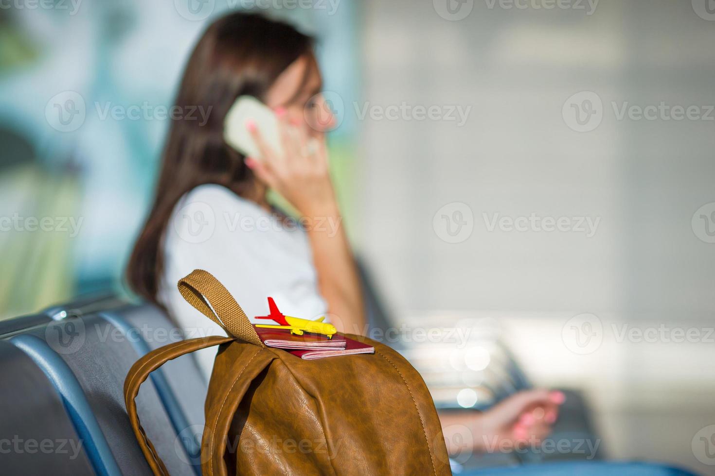 junge Frau, die am Telefon spricht, während sie an Bord wartet foto