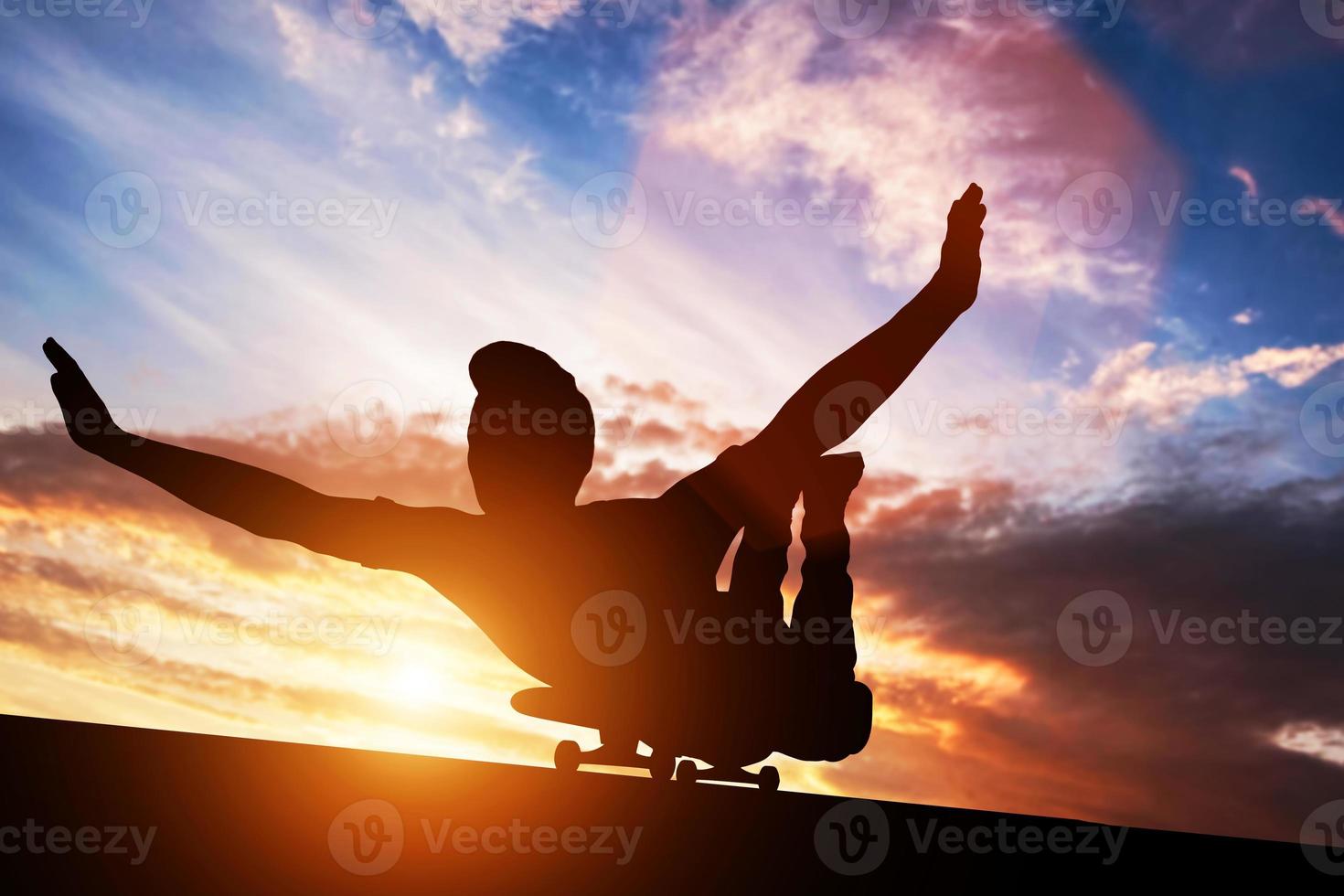 3D junger Mann, der bei Sonnenuntergang auf Skateboard liegt. foto