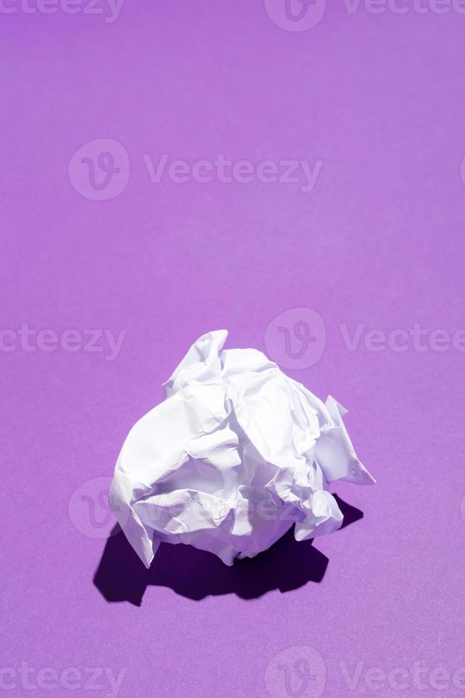 zerknittertes Blatt weißes Papier auf violettem Hintergrund foto