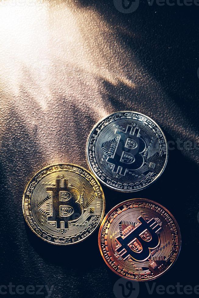 drei bunte Bitcoin-Münzen und Lichtstrahlen. foto