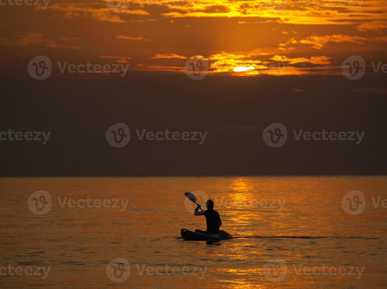 Silhouette des Mannes Kajak bei Sonnenuntergang foto