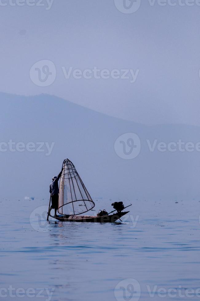 Fischer am inle See, der an einem Fuß arbeitet foto