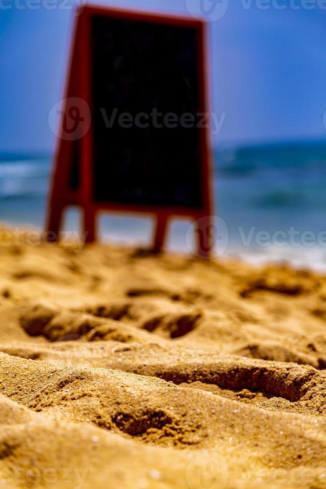 kreidetafel für text, nachricht oder werbung am sonnigen ozeanstrand foto