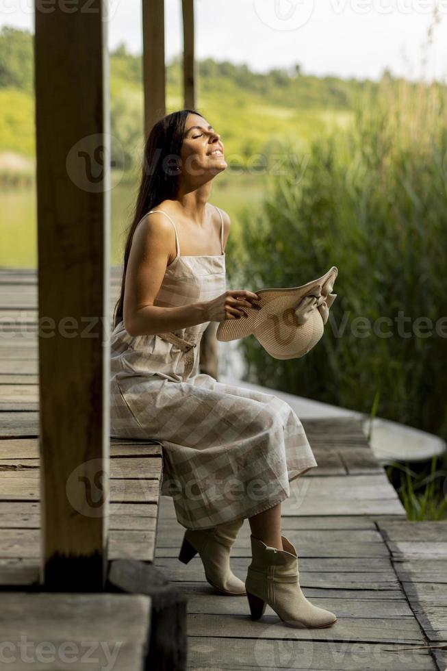 junge frau, die sich auf dem holzsteg am ruhigen see entspannt foto