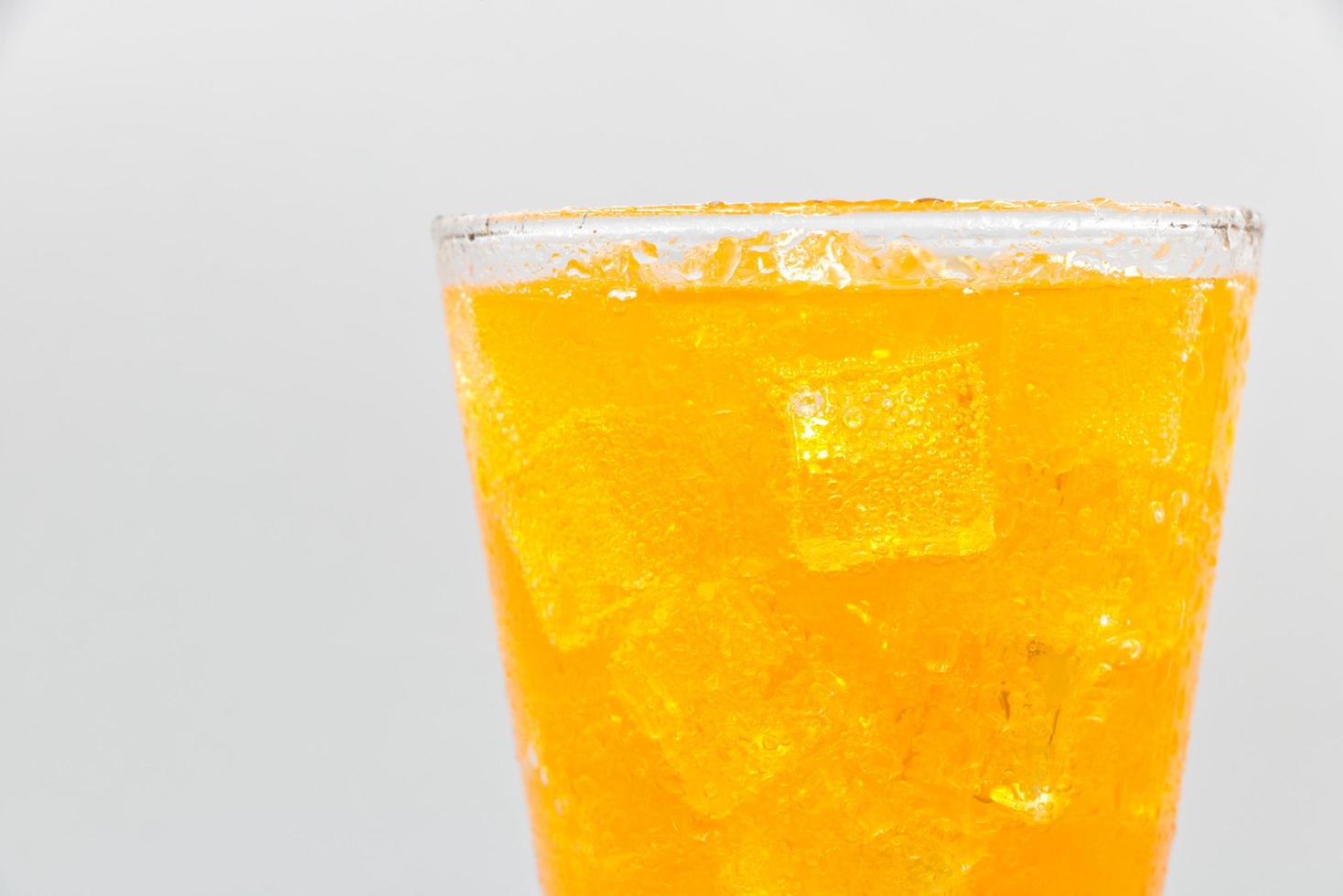 Orange Mineralwasser mit Eis im Glas auf weißem Hintergrund. foto