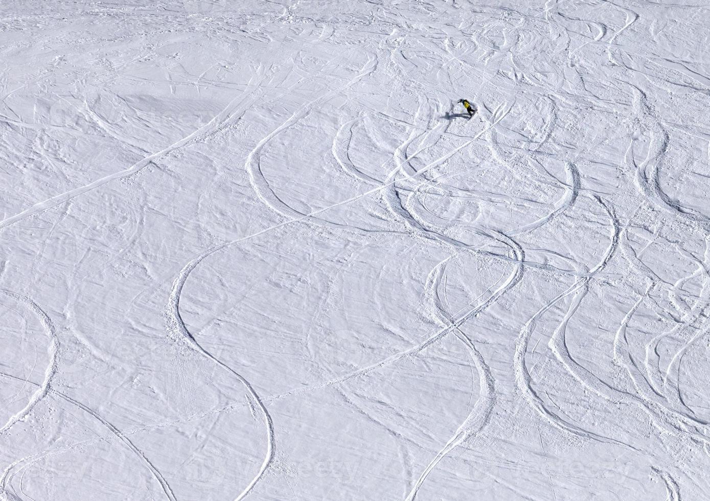 Snowboarder bergab auf Pistenhang mit Neuschnee foto