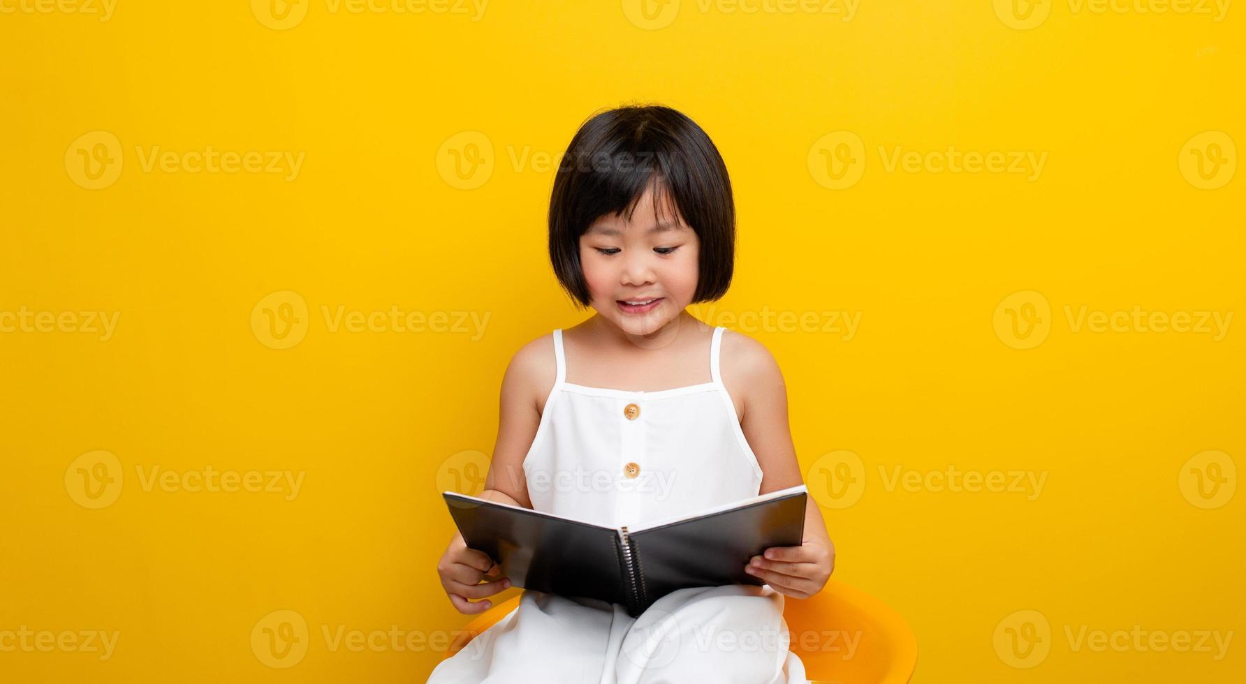 asiatische Mädchen sitzen und lesen ein Buch und lächeln glücklich. Selbstlesekonzept in der Kindheit. kluges Kind. kreatives kind. kluges Kind. foto