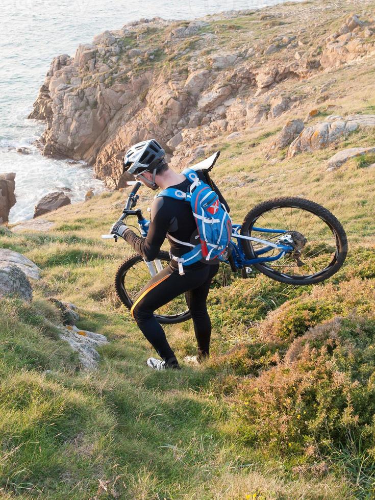 Radfahrer, der Ihr Fahrrad an der galizischen Küste trägt. foto