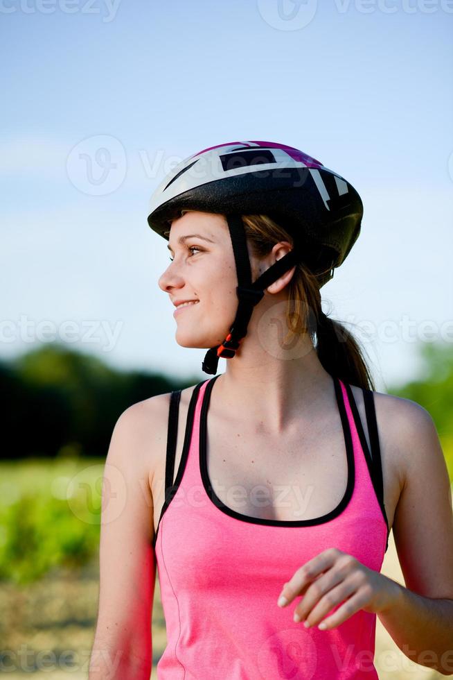 gesunde fröhliche junge Frau, die Mountainbike im Freien in der Landschaft reitet foto