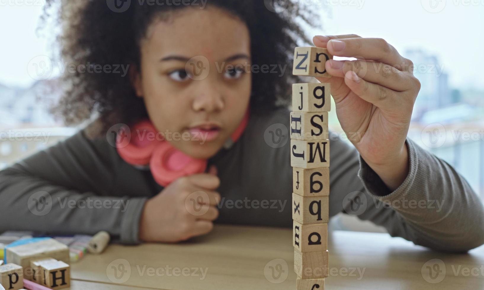 afrikanisch-amerikanischer Student, der Aktivitäten aus Holzblöcken für die Entwicklung zusammen mit Spaß und Spaß im Klassenzimmer spielt. foto