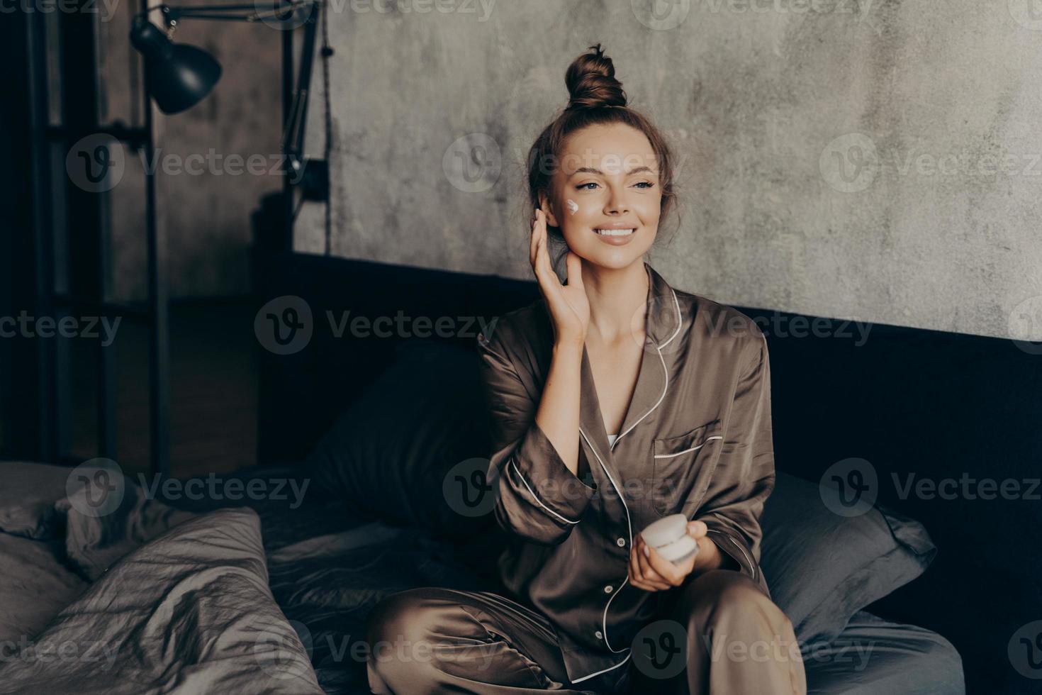 junge hübsche europäische frau im seidenpyjama kümmert sich um ihre haut und ihren körper foto