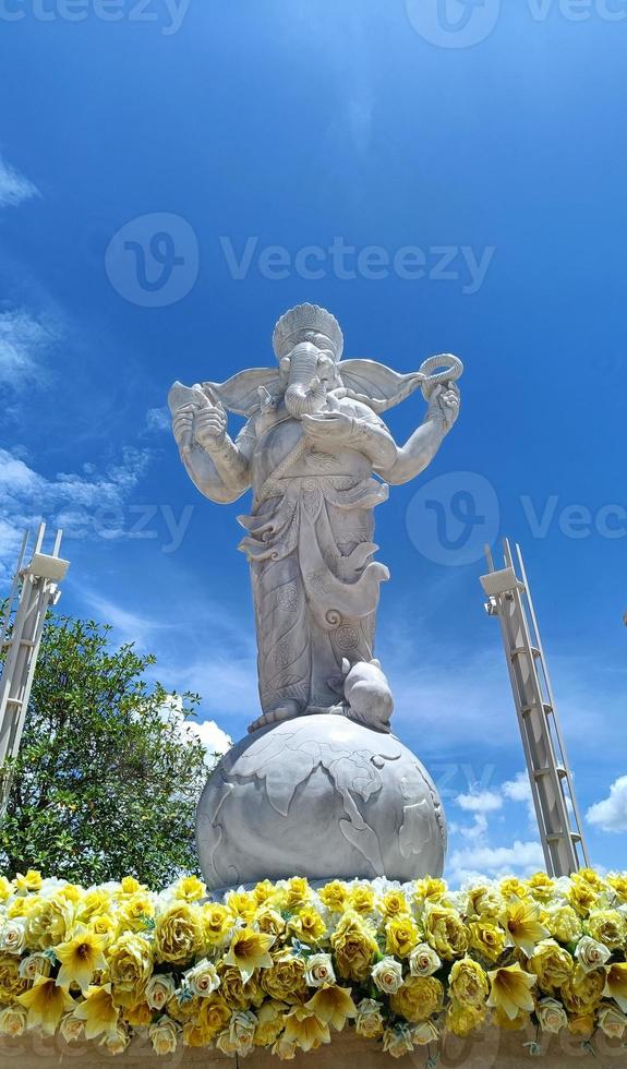 Ganesha-Statue und weiße Textur mit Blumen, Ganesha ist hinduistischer Gott des Erfolgs. Himmel Hintergrund foto