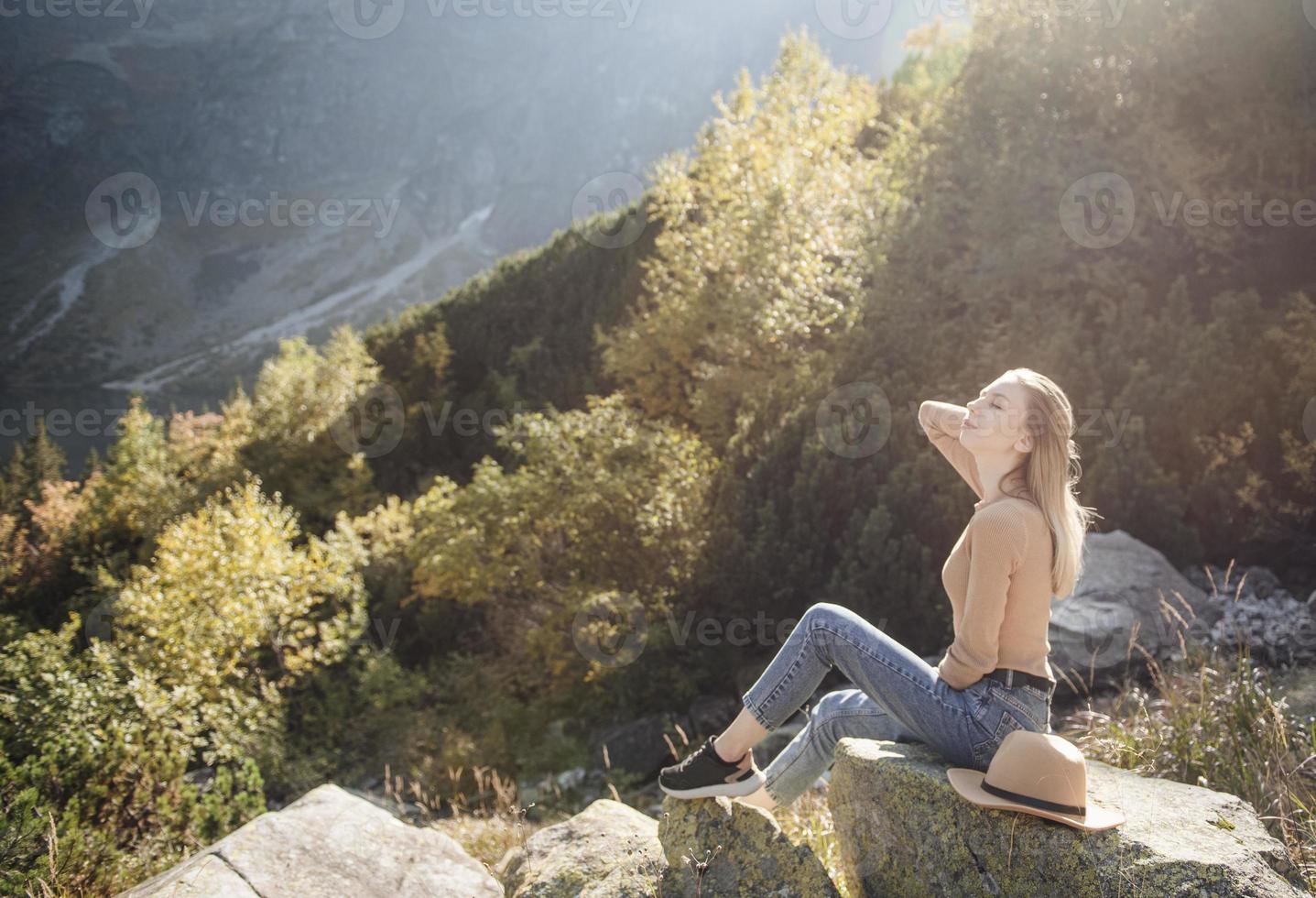 junge frau auf einer wanderung, die auf einem felsen sitzt foto