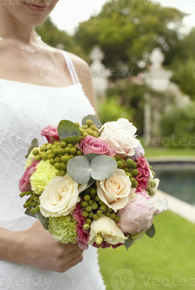Braut, die Blumenstrauß im Garten hält foto