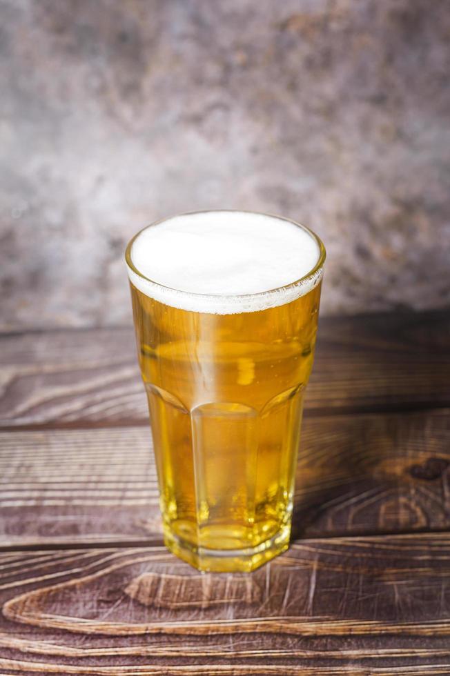 kaltes handwerkliches leichtes bier gießt aus der flasche auf den holztisch foto