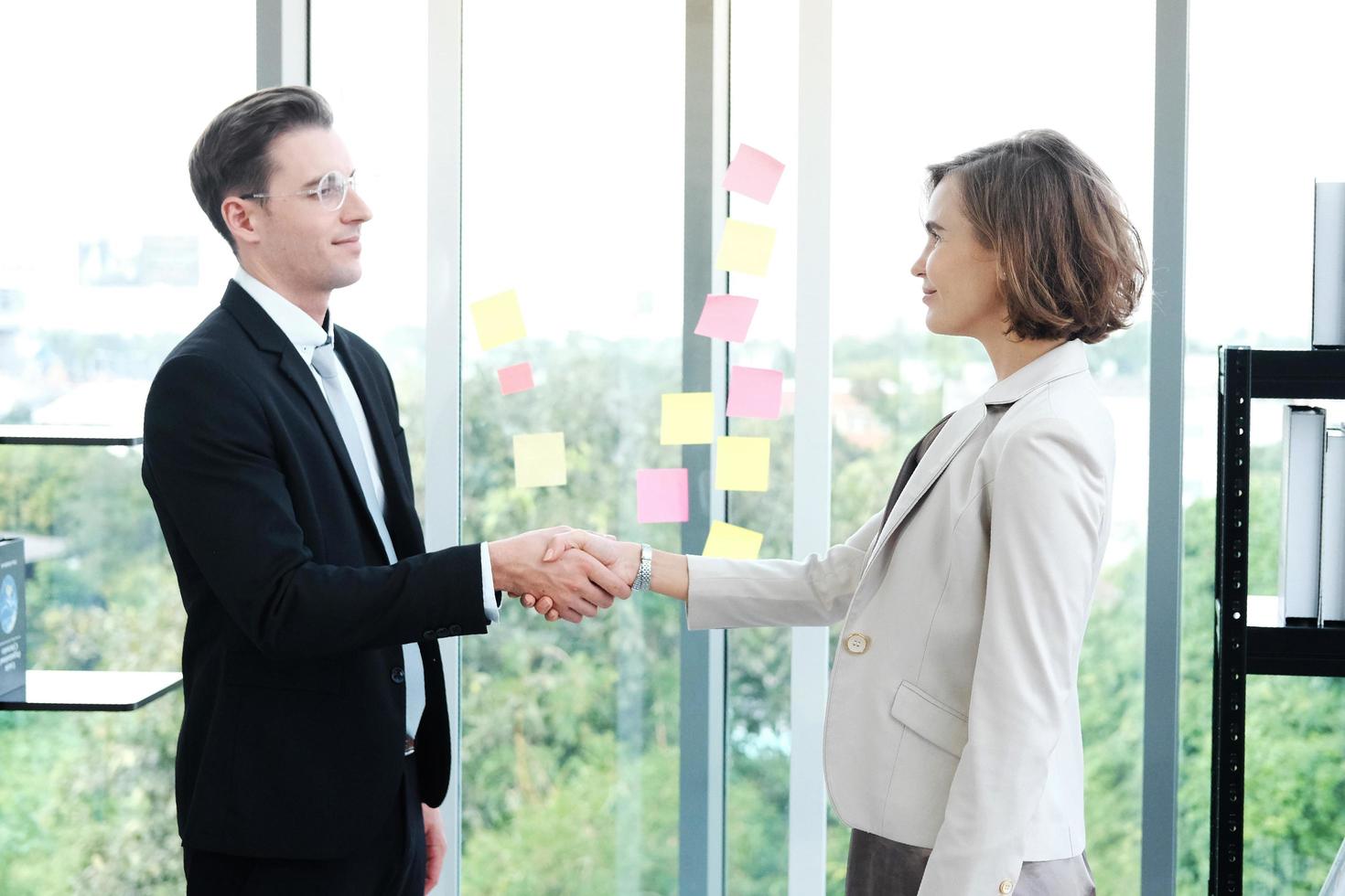 erfolgreicher geschäftsmann und geschäftsfrau glücklich und schütteln sich die hände, nachdem sie sich zur partnerschaft in einem modernen büro getroffen haben foto