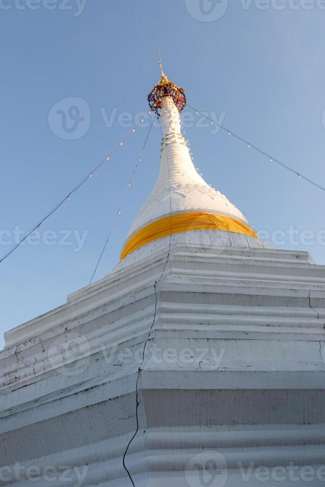 weiße Pagode mit dem goldenen Regenschirm auf dem Gipfel. foto