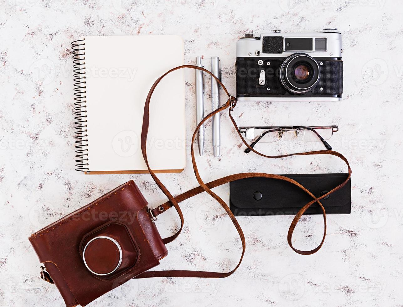 flache Lage, Draufsicht Bürotisch Schreibtisch. schreibtischarbeitsplatz mit retro-kamera, tagebuch, stift, brille, fall, tasse kaffee auf weißem hintergrund. foto