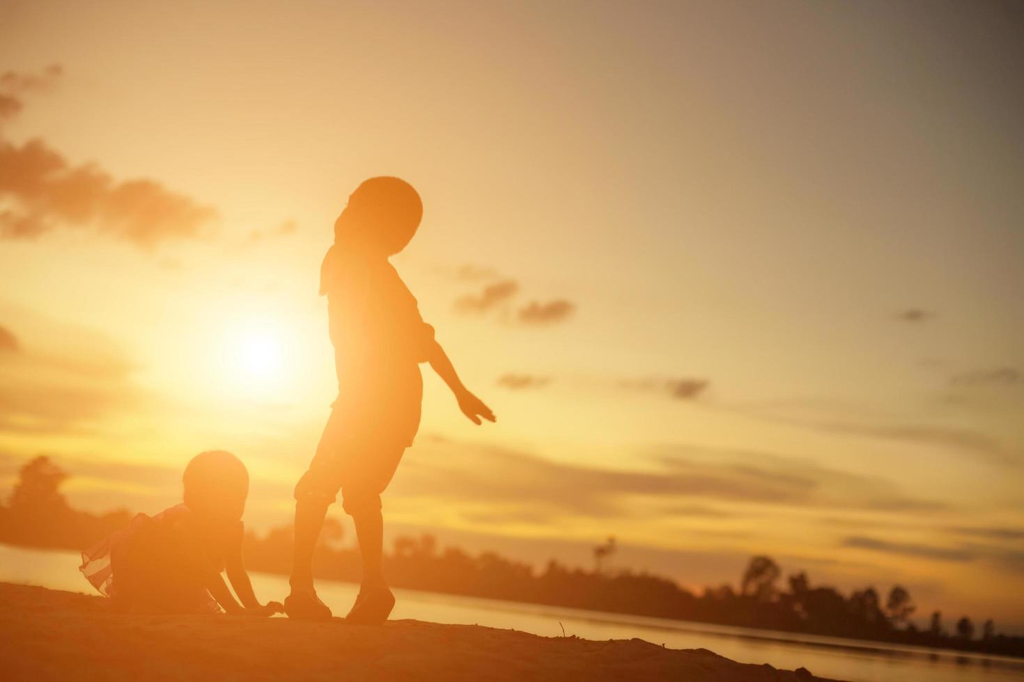 Silhouetten von Mutter und kleiner Tochter, die bei Sonnenuntergang spazieren gehen foto