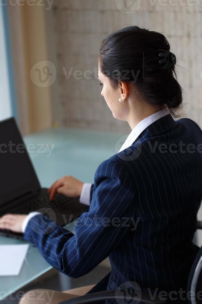 selbstbewusste Geschäftsfrau, die auf Laptoprückansicht tippt foto