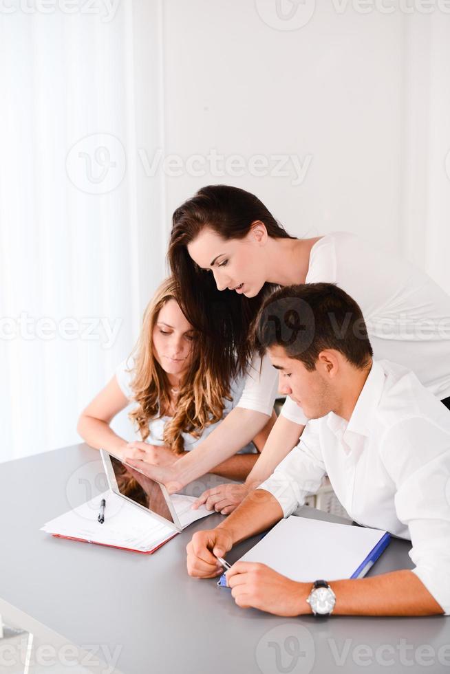 junge Privatlehrerin der schönen Frau, die zwei Schülern hilft, Hausaufgaben zu machen foto