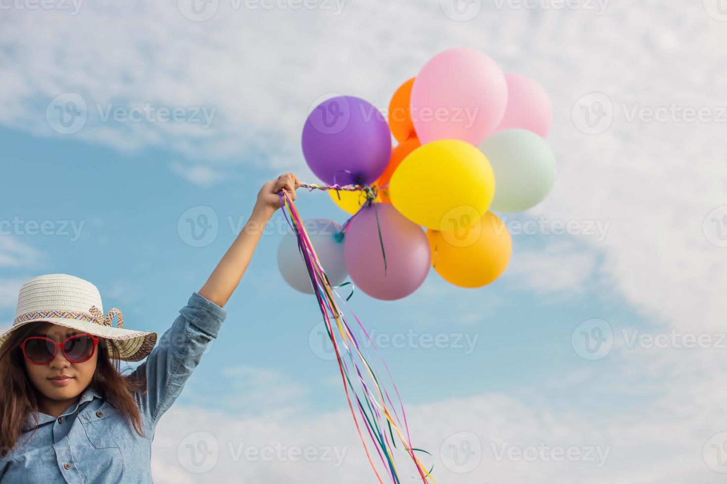 schönes Mädchen, das mit Luftballons am Strand springt foto