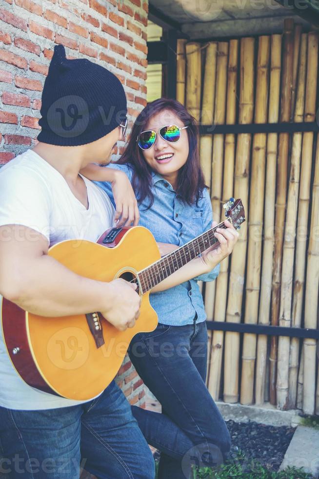 junger Hipster-Mann, der Gitarre spielt, um sich in seinem Urlaub zu entspannen, mit natürlicher und frischer Luft zu genießen. foto